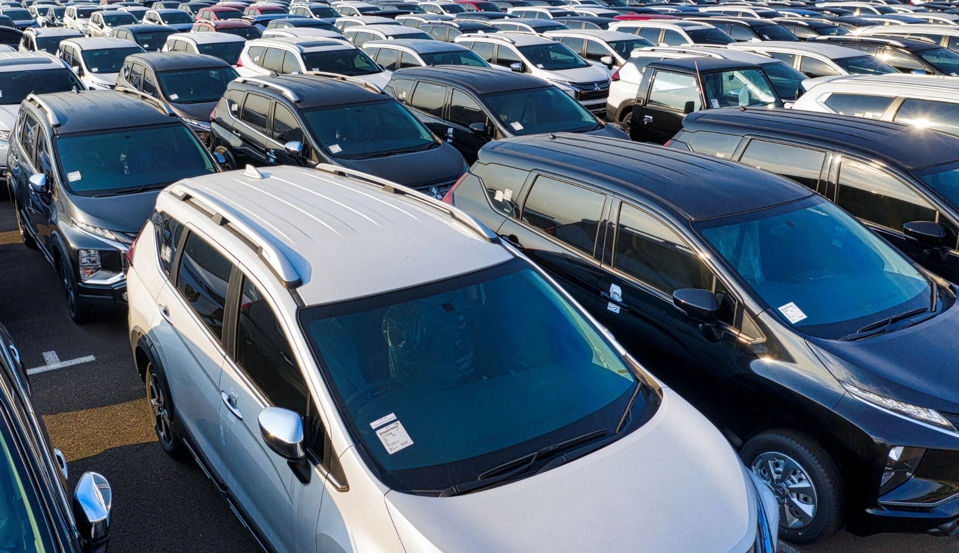 Different models of new cars parked at a dealership.